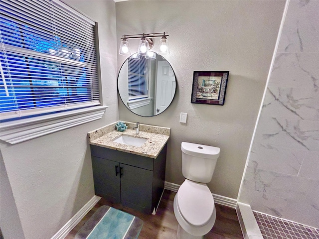 bathroom with vanity, toilet, wood finished floors, and baseboards