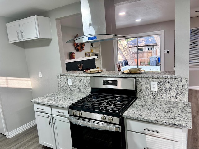 kitchen with light stone counters, gas stove, white cabinets, island range hood, and light wood finished floors