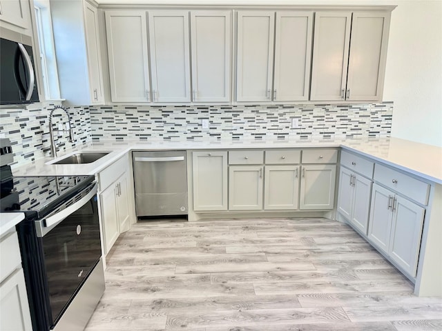 kitchen featuring light countertops, light wood-style flooring, tasteful backsplash, and appliances with stainless steel finishes