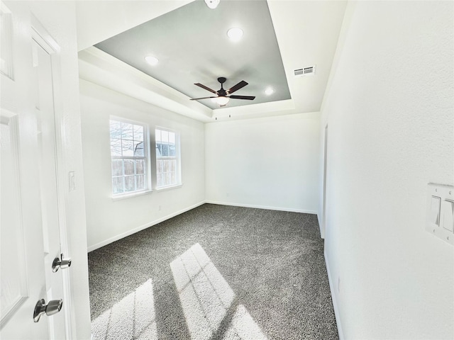 carpeted spare room featuring visible vents, baseboards, recessed lighting, a raised ceiling, and a ceiling fan