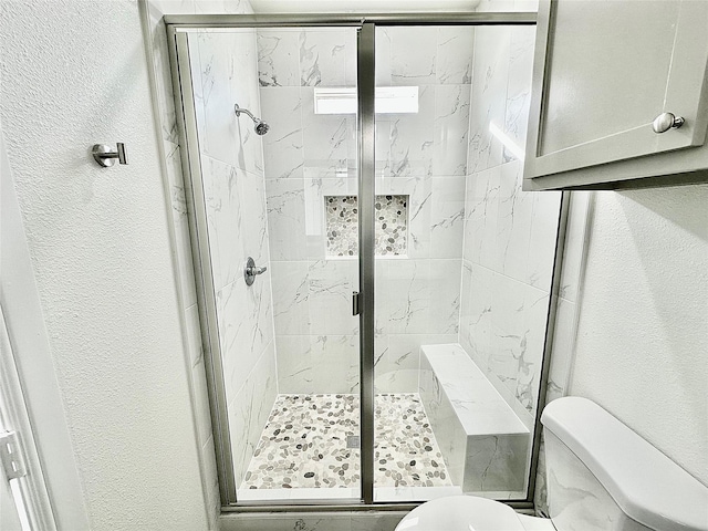 bathroom featuring a shower stall, toilet, and a textured wall