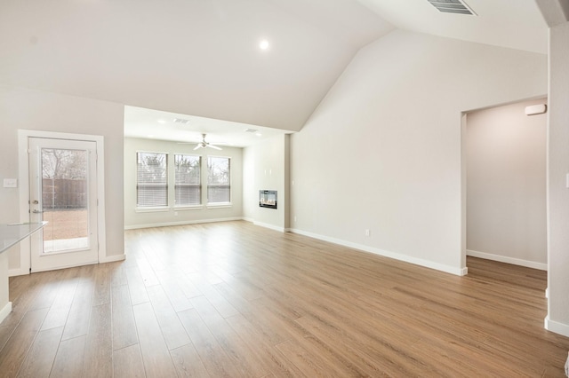 unfurnished living room with light wood finished floors, baseboards, lofted ceiling, a glass covered fireplace, and a ceiling fan