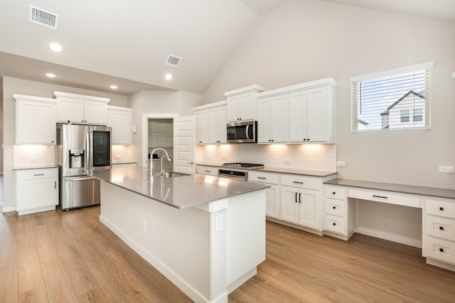 kitchen with a sink, stainless steel appliances, light wood-type flooring, and visible vents