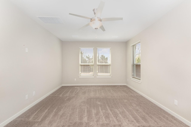 unfurnished room with light carpet, visible vents, a ceiling fan, and baseboards