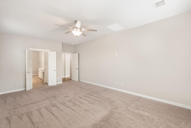 unfurnished bedroom featuring baseboards, visible vents, ensuite bathroom, and light carpet