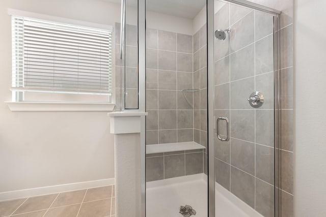 bathroom with tile patterned flooring, a stall shower, and baseboards