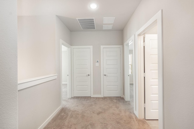 hall featuring visible vents, baseboards, and carpet floors