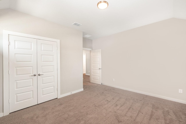 unfurnished bedroom featuring visible vents, baseboards, vaulted ceiling, carpet flooring, and a closet