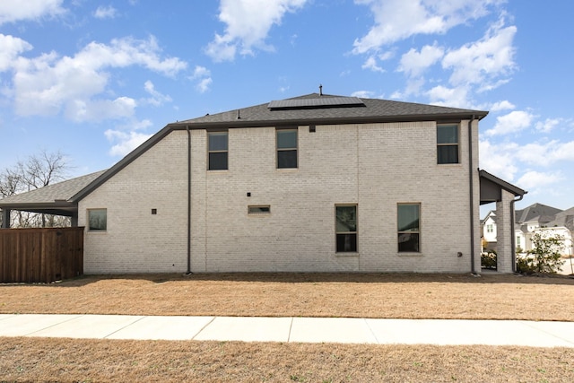 view of side of property featuring brick siding and solar panels