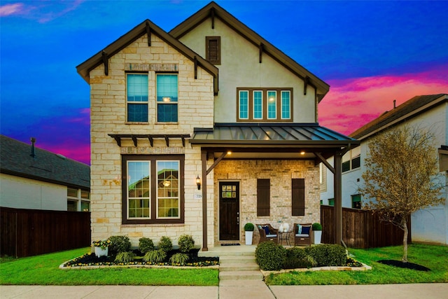 view of front of property featuring covered porch, a front yard, a standing seam roof, and fence