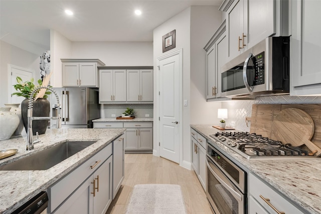 kitchen with a sink, appliances with stainless steel finishes, and gray cabinetry