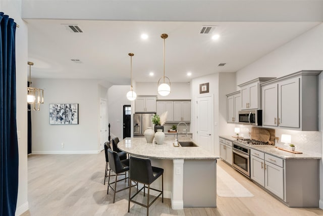 kitchen with visible vents, gray cabinets, appliances with stainless steel finishes, and a sink