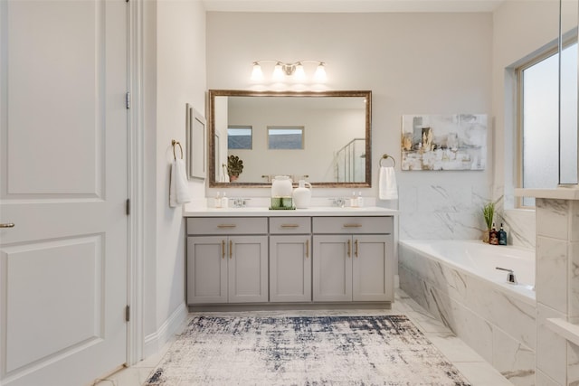 full bathroom featuring double vanity, a garden tub, and marble finish floor