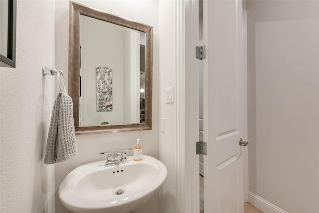 bathroom featuring baseboards and a sink