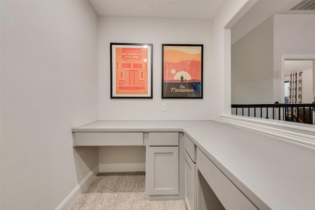 office space featuring light carpet, visible vents, built in study area, and baseboards