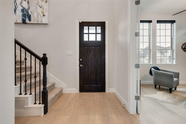 foyer with stairway, baseboards, and wood finished floors