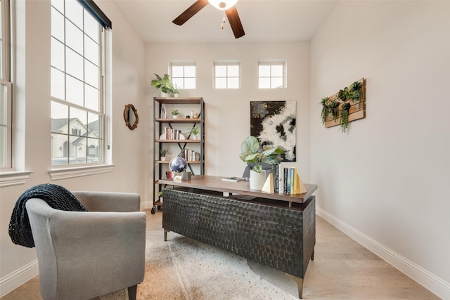 office space featuring baseboards, light wood-style floors, and a ceiling fan