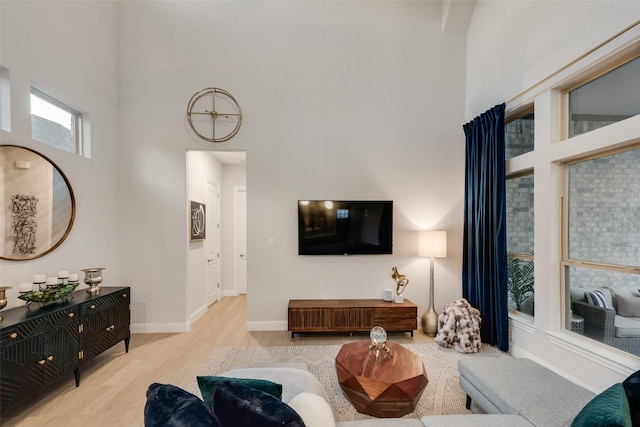 living area featuring baseboards, wood finished floors, and a towering ceiling