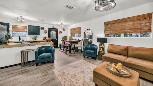 living room with light wood-style flooring, a healthy amount of sunlight, and visible vents