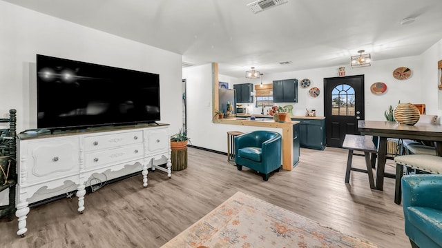 living area with light wood-style floors and visible vents