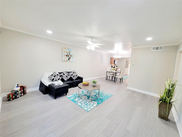 living room with baseboards, visible vents, light wood finished floors, and ornamental molding