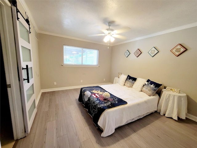 bedroom featuring wood finished floors, a barn door, crown molding, baseboards, and ceiling fan