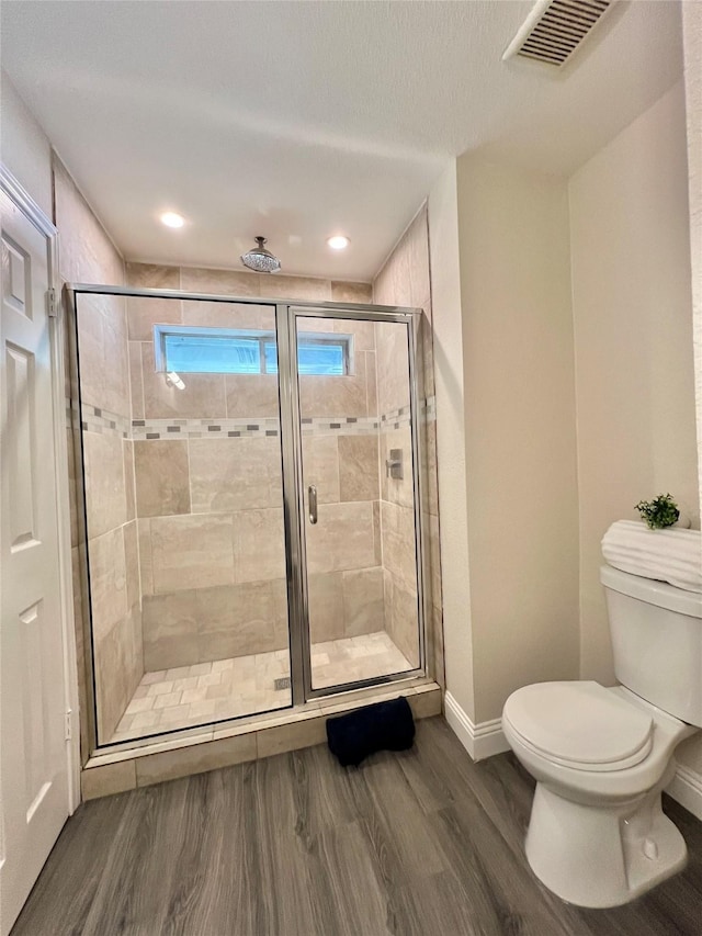 bathroom featuring wood finished floors, baseboards, visible vents, a stall shower, and toilet