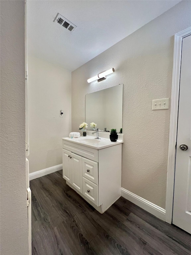 bathroom with vanity, wood finished floors, visible vents, and baseboards