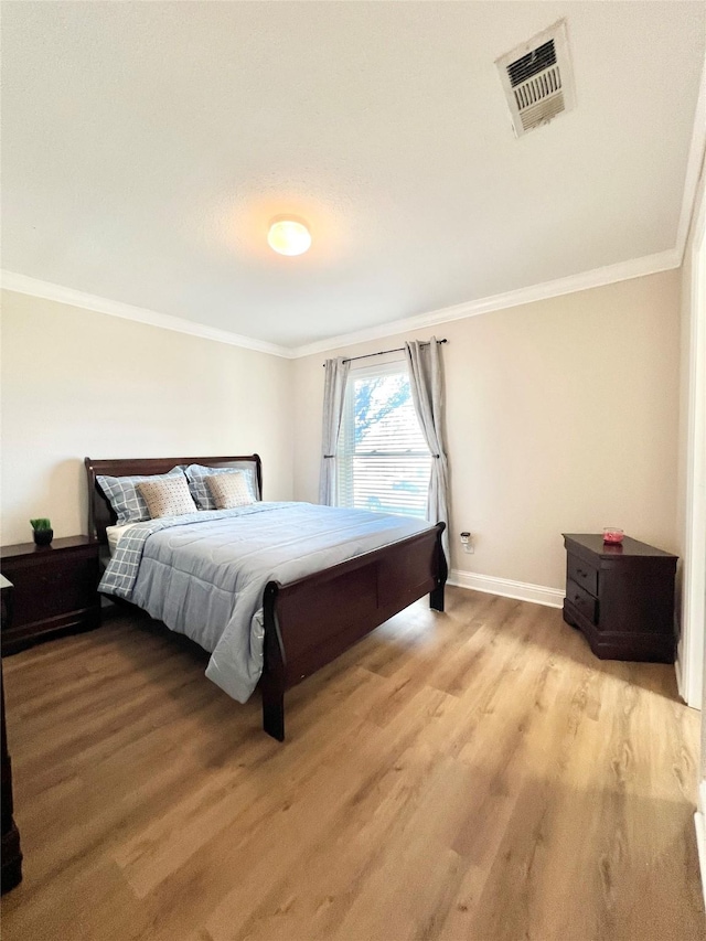 bedroom with visible vents, crown molding, and light wood-type flooring