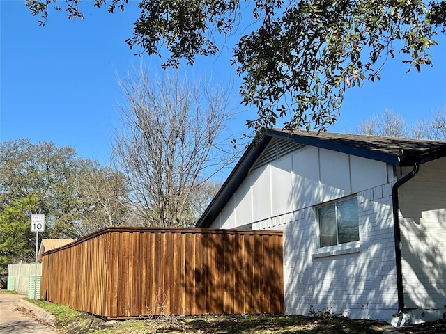 view of property exterior featuring fence and brick siding