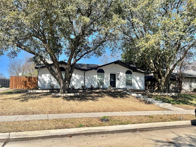 ranch-style house featuring an attached garage, fence, and stucco siding