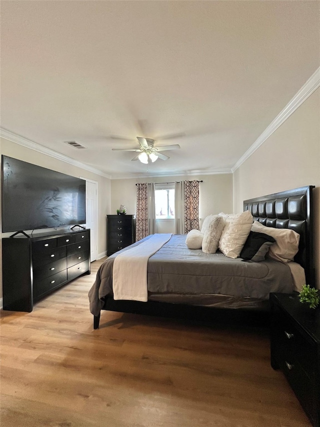 bedroom with visible vents, a ceiling fan, light wood-style flooring, and crown molding