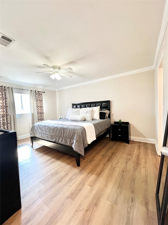 bedroom featuring light wood-style flooring, baseboards, visible vents, and ornamental molding