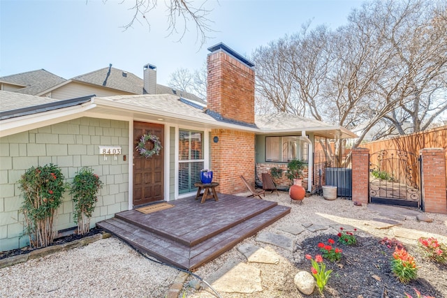 rear view of house featuring a gate, a shingled roof, a chimney, and fence