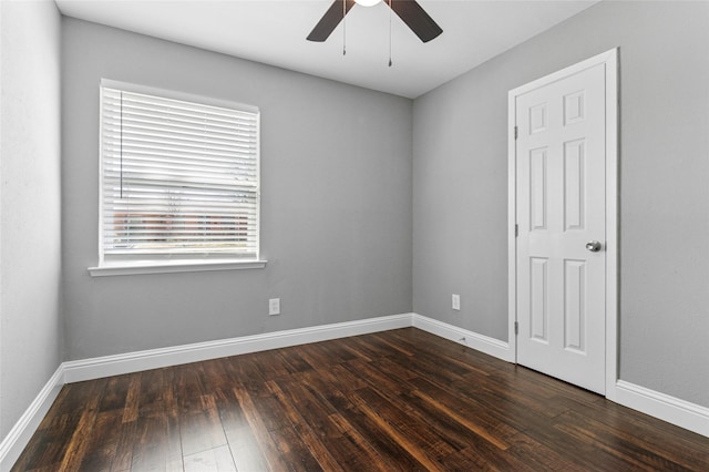 spare room with baseboards, a ceiling fan, and dark wood-style flooring