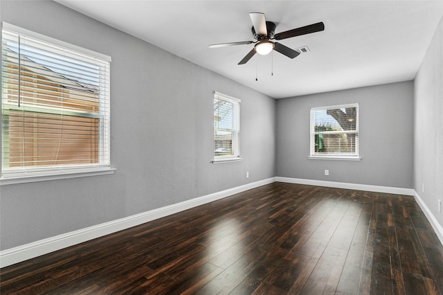 spare room with dark wood-type flooring, a ceiling fan, baseboards, and visible vents