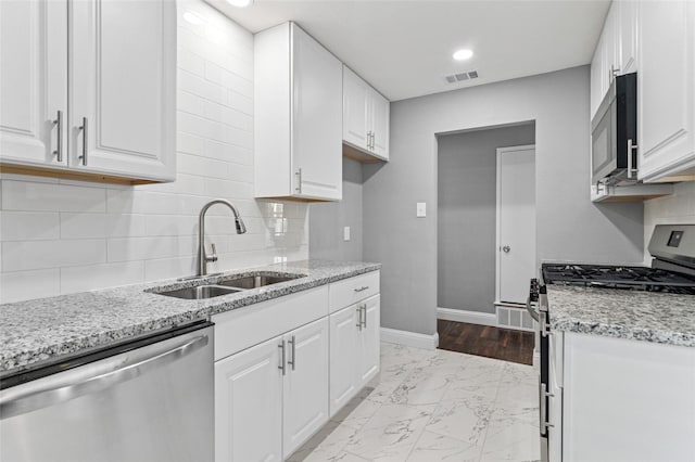 kitchen featuring visible vents, baseboards, appliances with stainless steel finishes, marble finish floor, and a sink