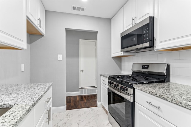 kitchen with light stone counters, visible vents, backsplash, and stainless steel appliances