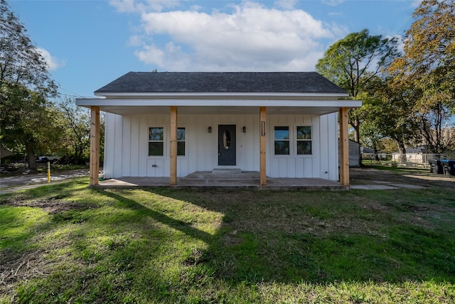 view of front of home featuring covered porch, board and batten siding, a front lawn, and roof with shingles