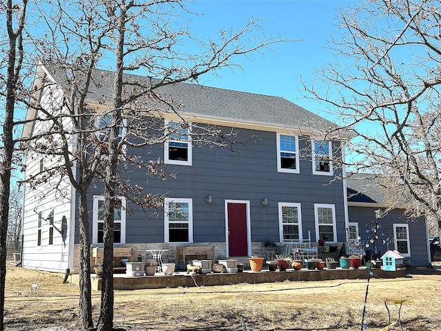 colonial house featuring a patio area and a shingled roof