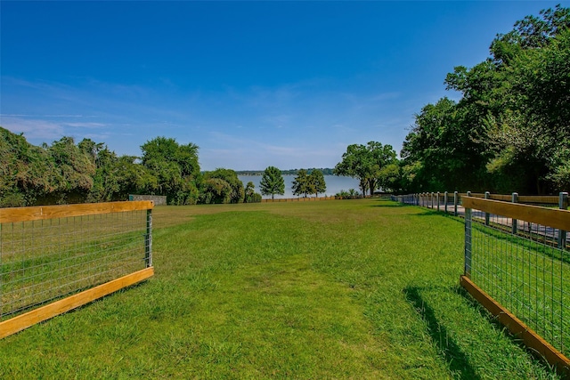 view of yard with a rural view, a water view, and fence