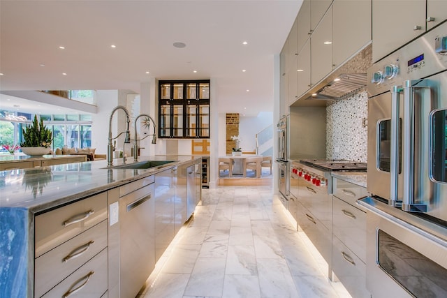 kitchen with a sink, backsplash, modern cabinets, and appliances with stainless steel finishes