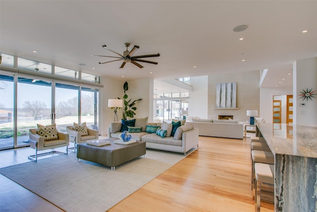 living room with recessed lighting, a wall of windows, and light wood-style floors