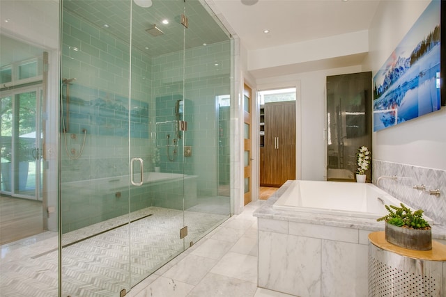 bathroom featuring a garden tub, a wealth of natural light, and a shower stall