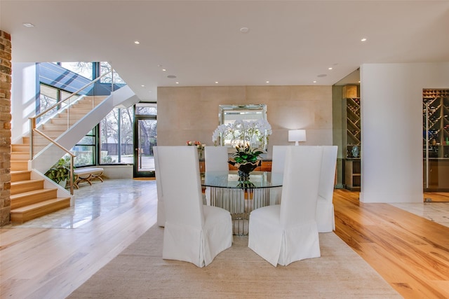 dining space featuring recessed lighting, floor to ceiling windows, stairway, and wood finished floors