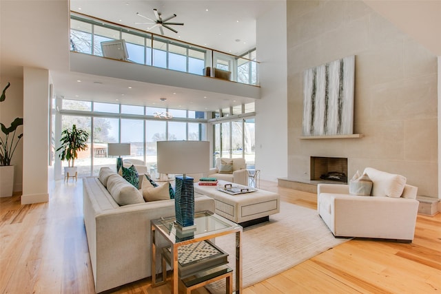 living area featuring wood finished floors, floor to ceiling windows, a fireplace, and a towering ceiling