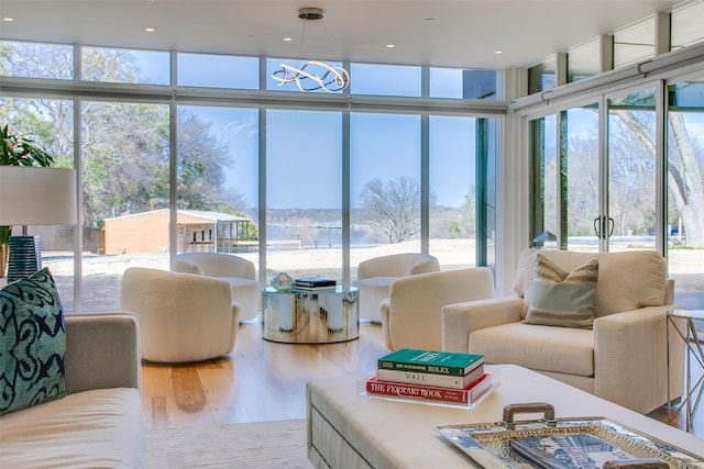 living room featuring a wealth of natural light, a chandelier, wood finished floors, and a wall of windows