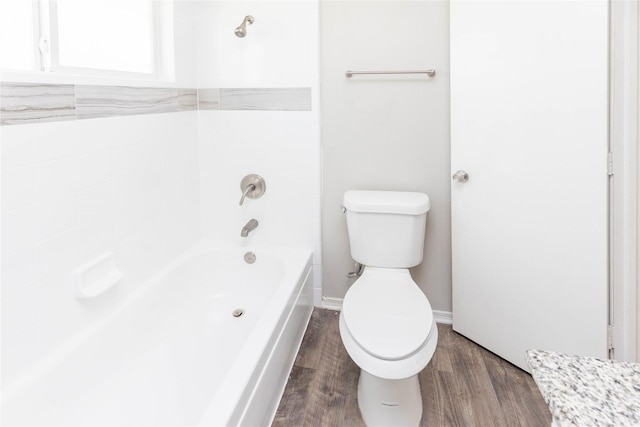 full bath with baseboards, toilet, wood finished floors, and bathtub / shower combination