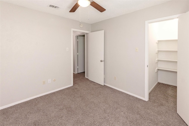 spare room featuring visible vents, baseboards, carpet floors, a textured ceiling, and a ceiling fan