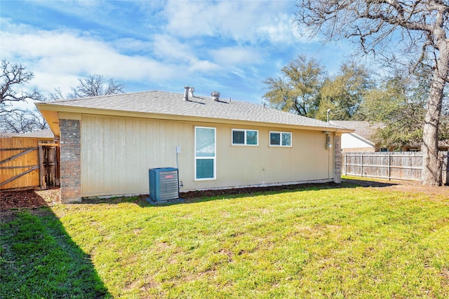 rear view of house with cooling unit, a lawn, and a fenced backyard